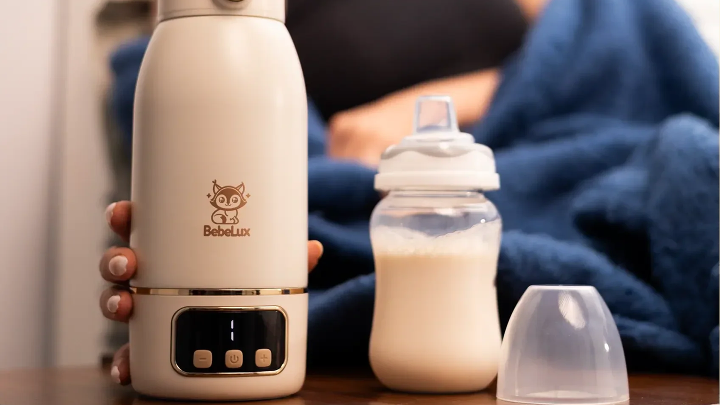 Hand haelt den BebeWarm Flaschenwaermer neben einer gefuellten Babyflasche